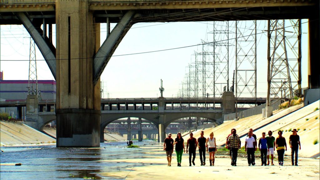 Contestants walk along the LA river bed