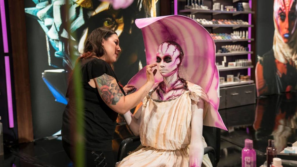 Makeup artist applies floral makeup to female model